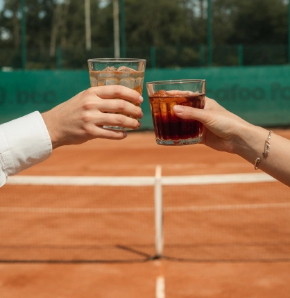 Dos personas brindando en una cancha de Tenis